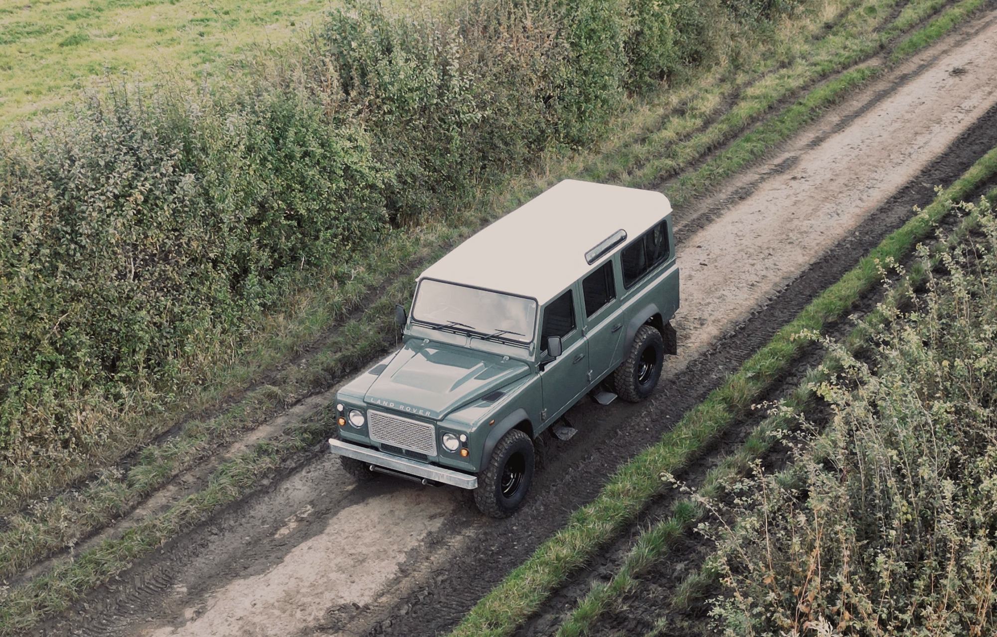 An aerial view of a Land Rover Defender on a country lane through Hampshire farmland.