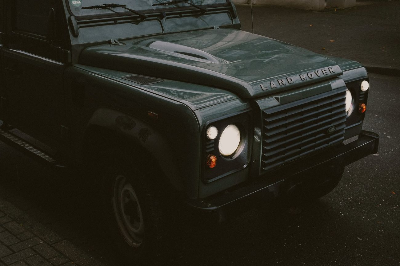 A Land Rover Defender's headlights at dusk.