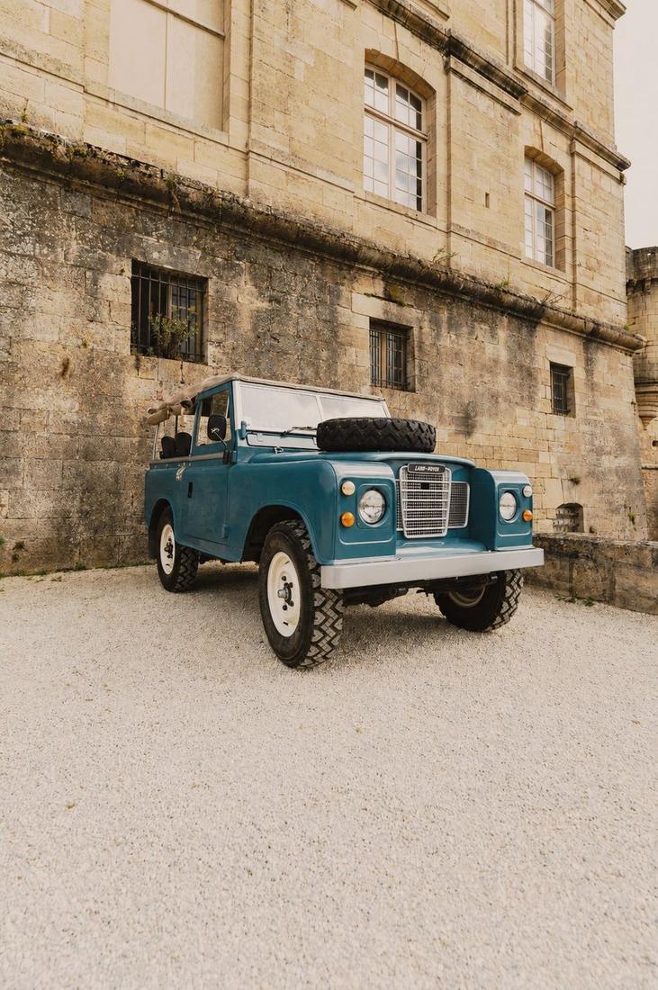 A Series Land Rover parked outside a stone estate building.